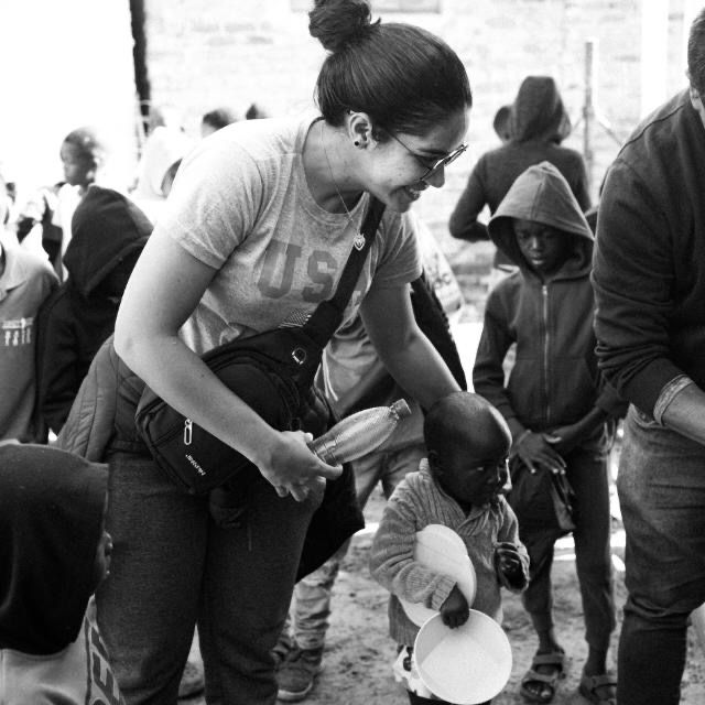 Letícia servindo água a uma criança na África do Sul