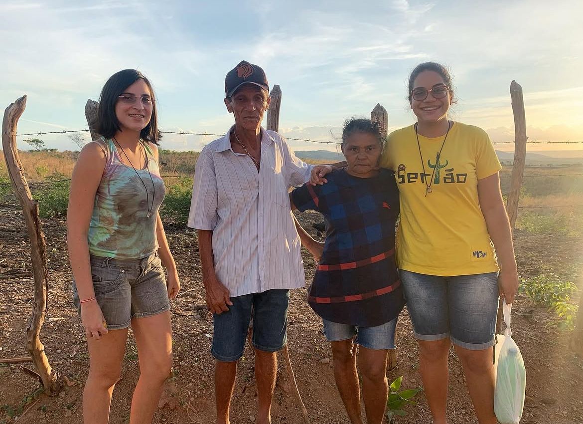 Letícia com uma família no sertão nordestino ao entardecer