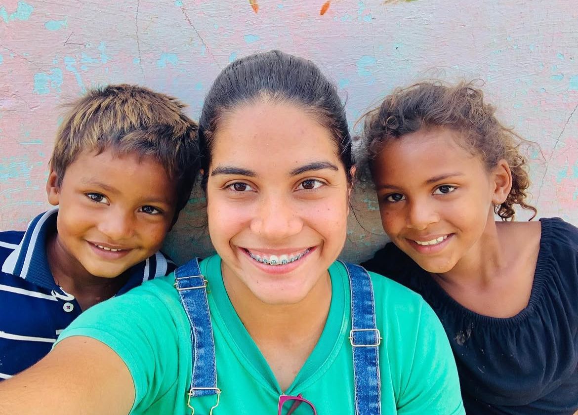 Letícia sorrindo com duas crianças do sertão